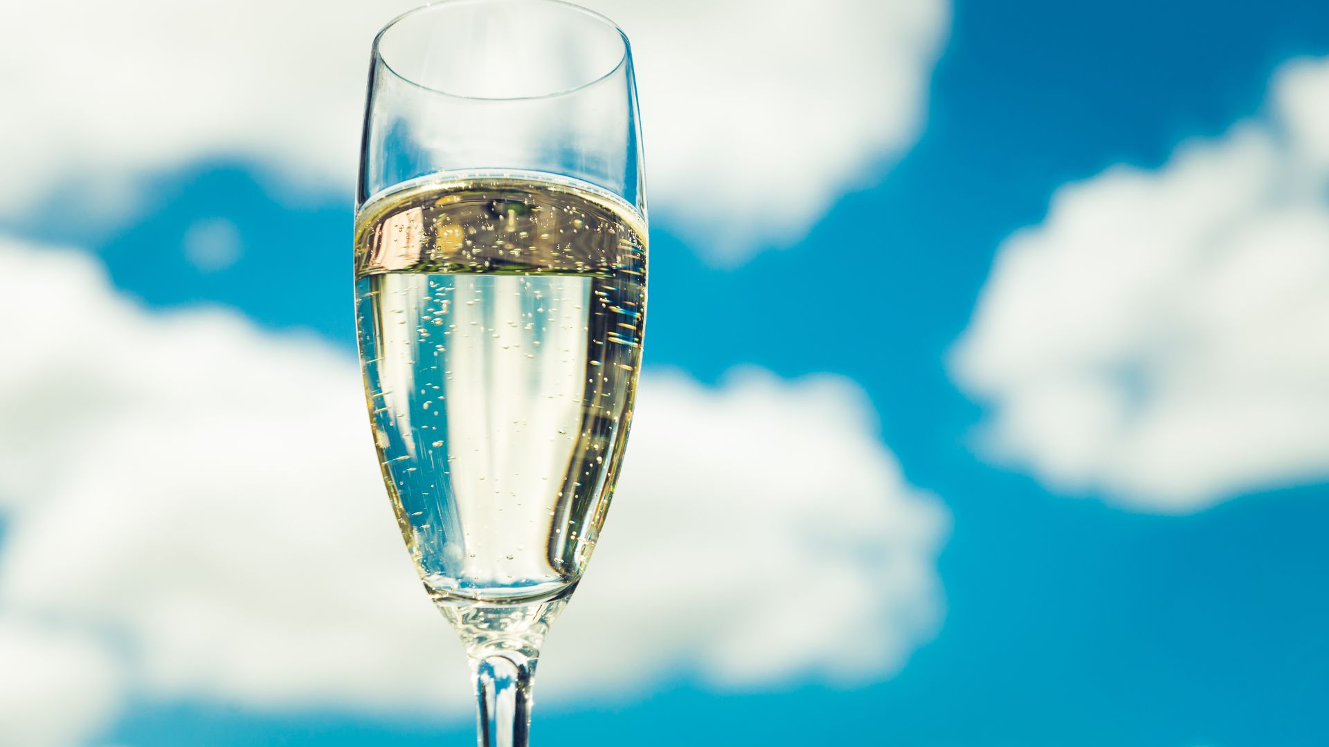 a glass of prosecco against a blue sky